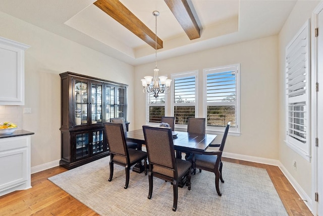 dining space with beam ceiling, a raised ceiling, an inviting chandelier, light wood-type flooring, and baseboards