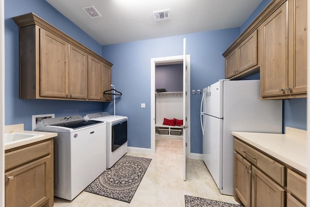 laundry area with cabinet space, a sink, visible vents, and washer and dryer