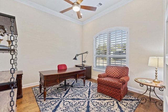 home office featuring baseboards, visible vents, ceiling fan, ornamental molding, and wood finished floors