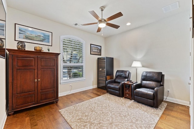 sitting room with a ceiling fan, baseboards, visible vents, and wood finished floors