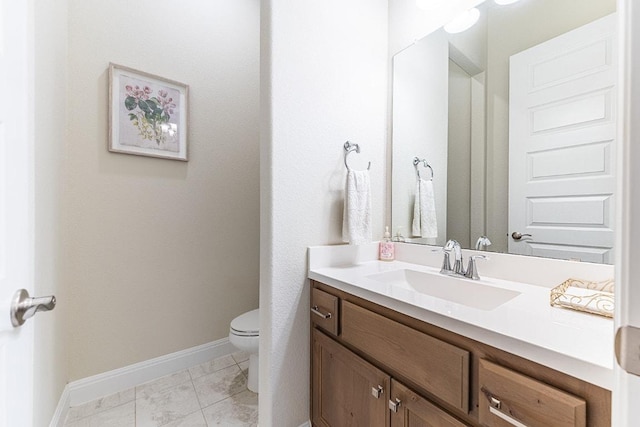 bathroom featuring vanity, toilet, and baseboards