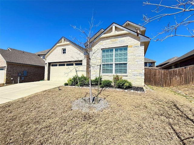 view of front of property with an attached garage, concrete driveway, stone siding, and fence