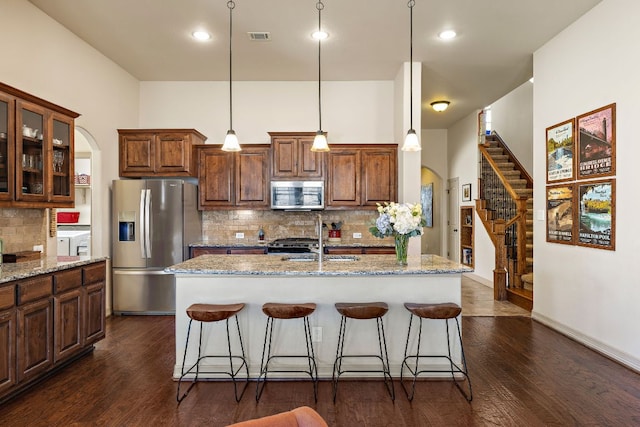 kitchen with washer / dryer, visible vents, arched walkways, a breakfast bar area, and stainless steel appliances