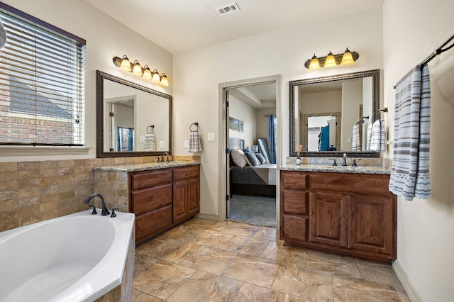 ensuite bathroom with a garden tub, a sink, two vanities, visible vents, and ensuite bath