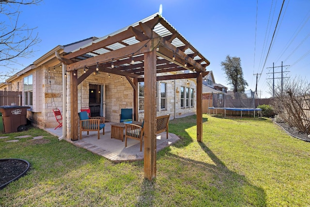 rear view of house featuring a trampoline, a patio, a lawn, a pergola, and stone siding