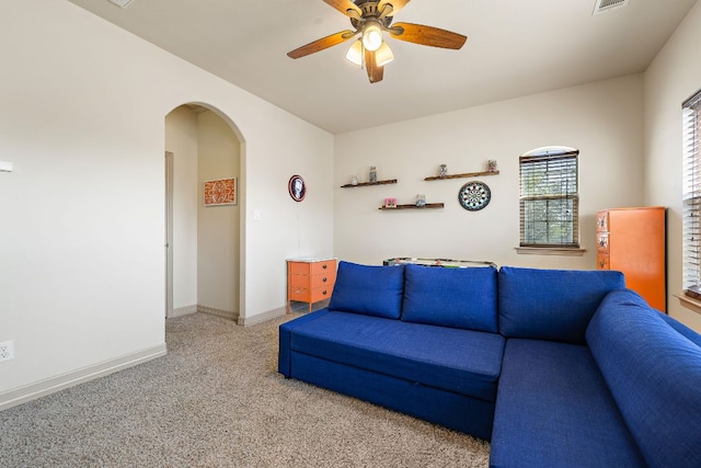 living area featuring arched walkways, visible vents, a ceiling fan, carpet flooring, and baseboards