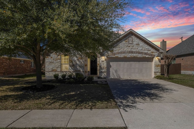 view of front facade with a garage, stone siding, and driveway