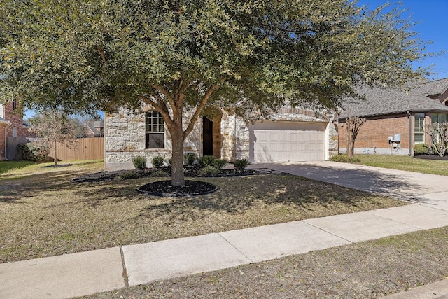 view of property hidden behind natural elements featuring a front yard, fence, a garage, stone siding, and driveway