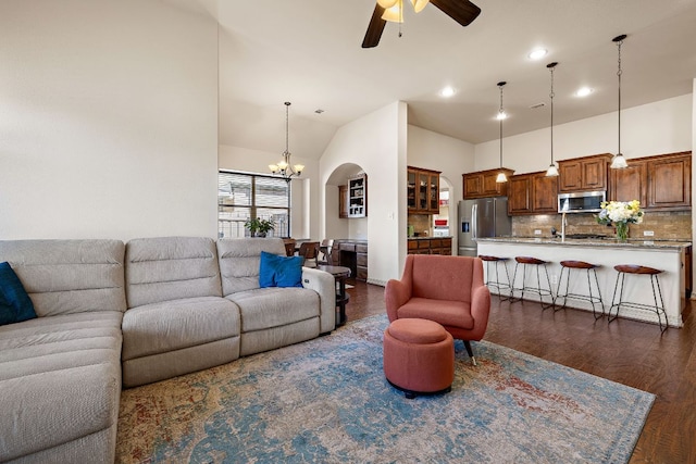 living room featuring dark wood-type flooring, recessed lighting, a high ceiling, and ceiling fan with notable chandelier