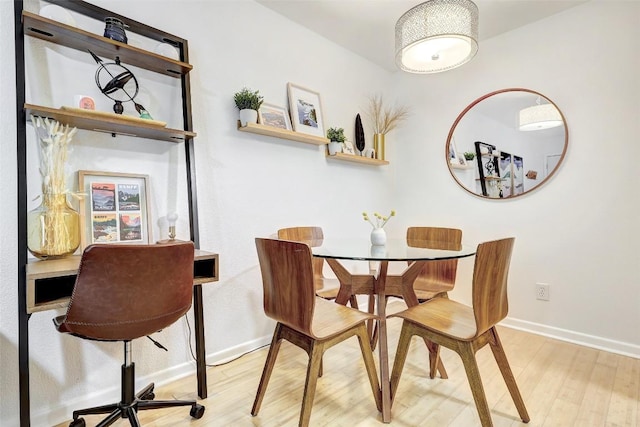 dining space with light wood-type flooring and baseboards