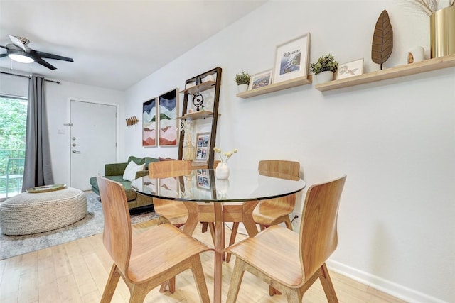 dining area featuring light wood-style flooring, baseboards, and ceiling fan