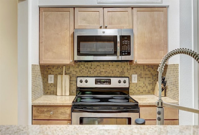 kitchen with light brown cabinets, appliances with stainless steel finishes, backsplash, and light stone countertops