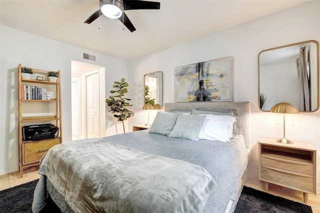 bedroom with ceiling fan, visible vents, and wood finished floors