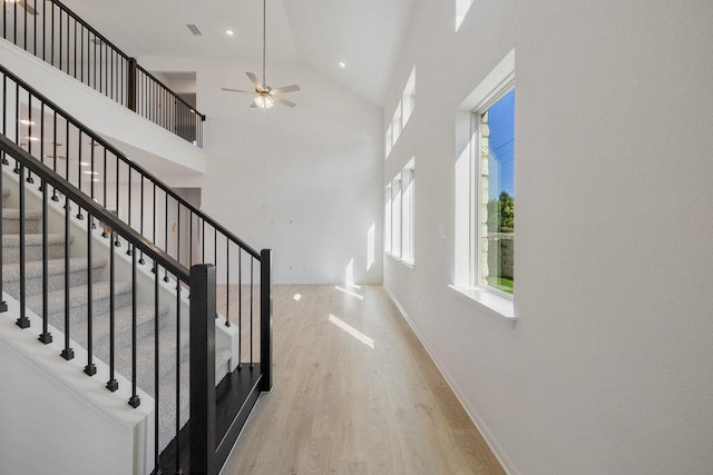 stairway featuring visible vents, baseboards, a ceiling fan, wood finished floors, and high vaulted ceiling