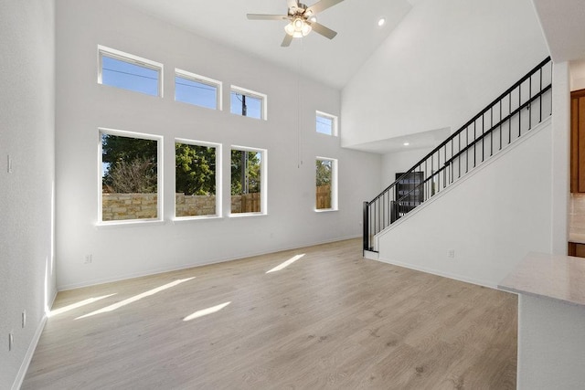 unfurnished living room featuring recessed lighting, a ceiling fan, baseboards, stairs, and light wood-style floors