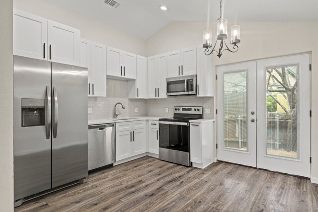 kitchen with white cabinets, appliances with stainless steel finishes, vaulted ceiling, light countertops, and a sink