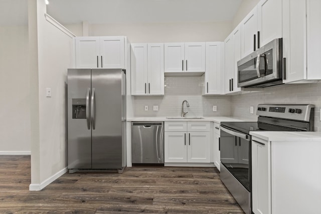 kitchen with dark wood-style floors, stainless steel appliances, light countertops, white cabinetry, and a sink