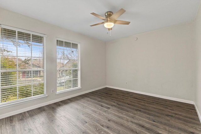 unfurnished room featuring baseboards, dark wood finished floors, and a ceiling fan