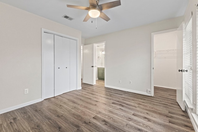 unfurnished bedroom featuring a closet, wood finished floors, visible vents, and baseboards