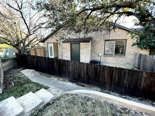 view of property exterior with brick siding and fence private yard