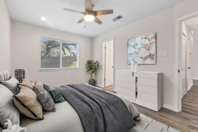 bedroom featuring baseboards, visible vents, ceiling fan, and wood finished floors