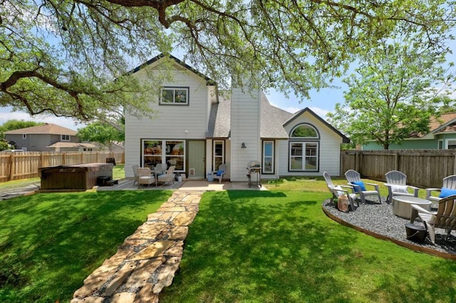 back of property with a patio, a fenced backyard, a lawn, roof with shingles, and a hot tub