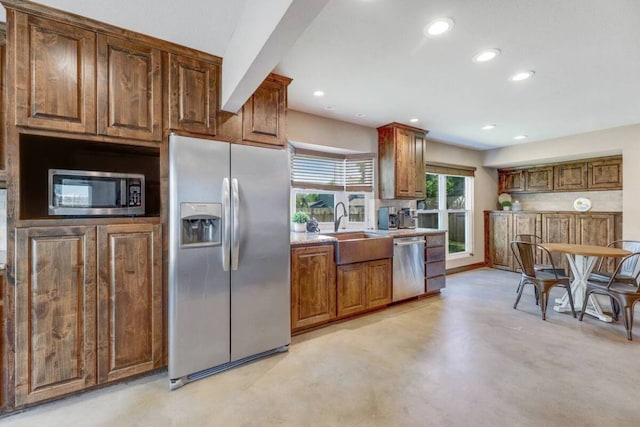 kitchen featuring appliances with stainless steel finishes, finished concrete floors, light countertops, a sink, and recessed lighting