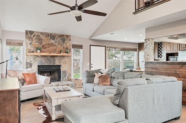 living room with visible vents, high vaulted ceiling, ceiling fan, and a stone fireplace