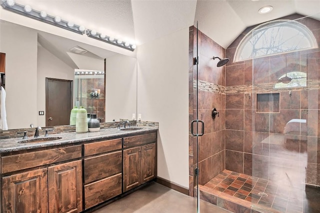 full bath featuring vaulted ceiling, a sink, a shower stall, and double vanity