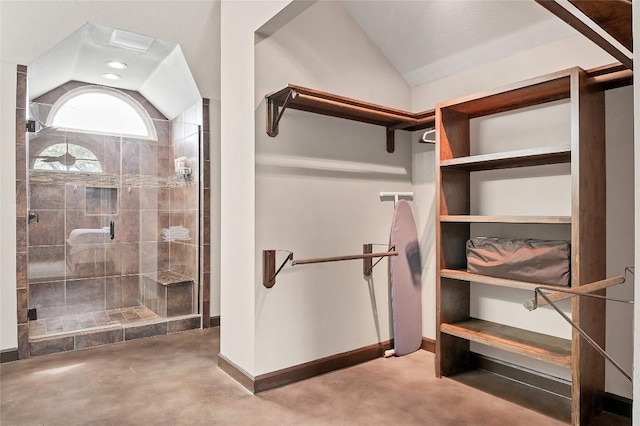 full bathroom featuring concrete floors, vaulted ceiling, a tile shower, and baseboards