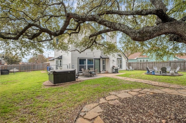 rear view of property with a patio area, a hot tub, a fire pit, and a fenced backyard