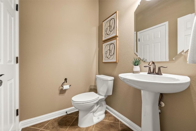 bathroom with toilet, baseboards, and tile patterned floors