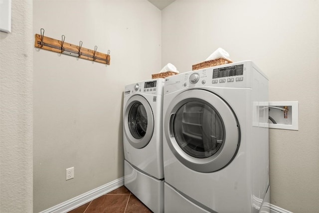 laundry room with dark tile patterned flooring, laundry area, baseboards, and separate washer and dryer