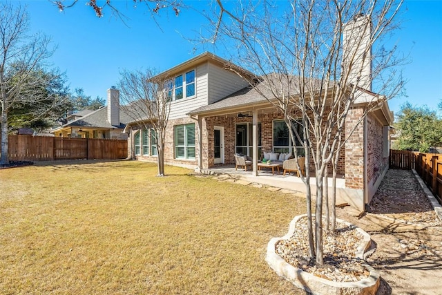 back of house with a fenced backyard, brick siding, a ceiling fan, a lawn, and a patio area