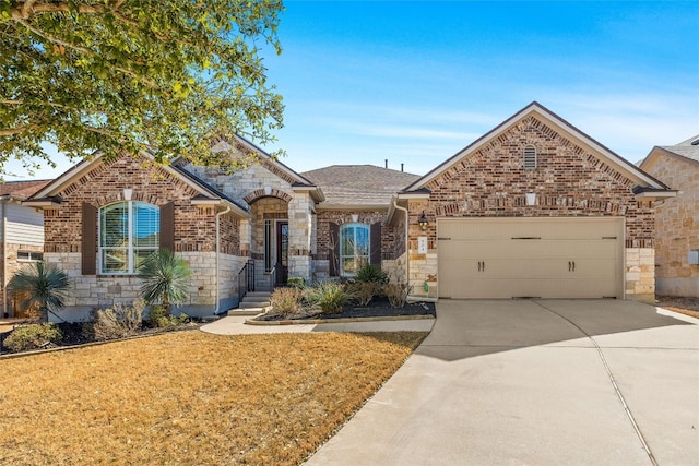 french country inspired facade with a garage, brick siding, driveway, stone siding, and a front yard