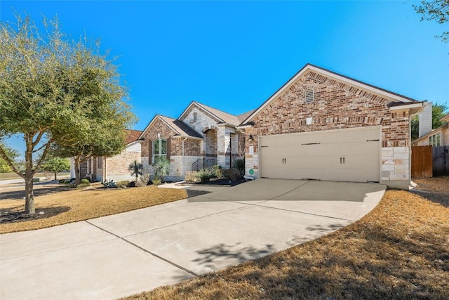 view of front of home with brick siding, an attached garage, fence, stone siding, and driveway