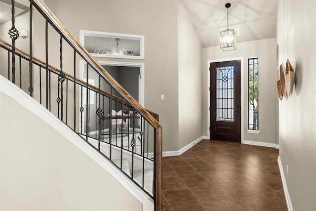 tiled foyer entrance featuring stairs, baseboards, and a chandelier