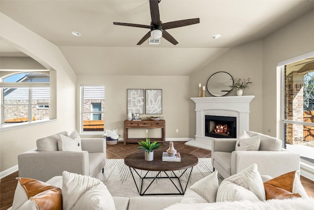 tiled living room with a warm lit fireplace, vaulted ceiling, visible vents, and baseboards