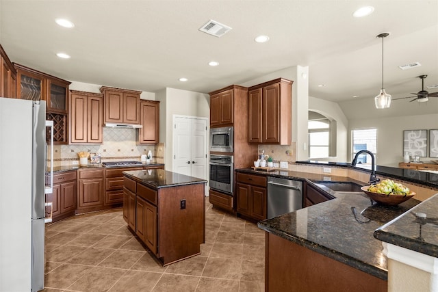 kitchen featuring appliances with stainless steel finishes, a kitchen island, a sink, and visible vents