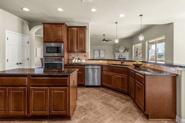 kitchen with recessed lighting, a sink, hanging light fixtures, appliances with stainless steel finishes, and dark stone countertops