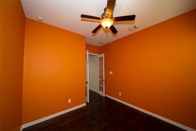 spare room featuring a ceiling fan, wood finished floors, visible vents, and baseboards