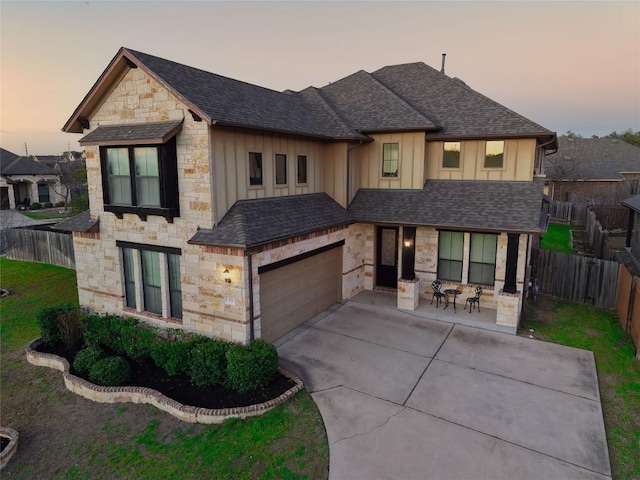 view of front of home with a garage, roof with shingles, board and batten siding, and fence