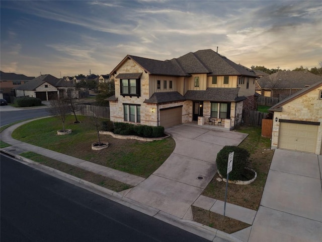 view of front facade featuring driveway, stone siding, an attached garage, fence, and a front lawn