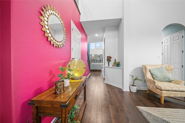 hall featuring arched walkways, hardwood / wood-style floors, and baseboards