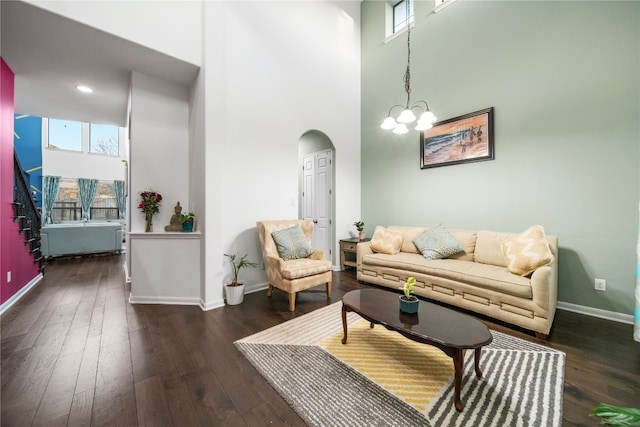 living area featuring a towering ceiling, baseboards, arched walkways, and hardwood / wood-style floors