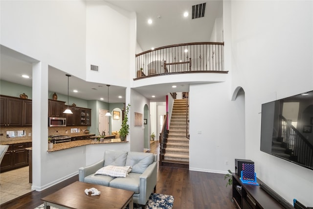 living room with visible vents, arched walkways, and wood finished floors