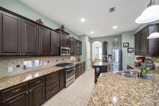 kitchen with visible vents, arched walkways, appliances with stainless steel finishes, dark brown cabinets, and a sink