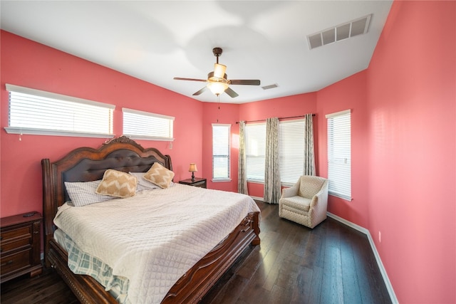 bedroom with ceiling fan, dark wood finished floors, visible vents, and baseboards