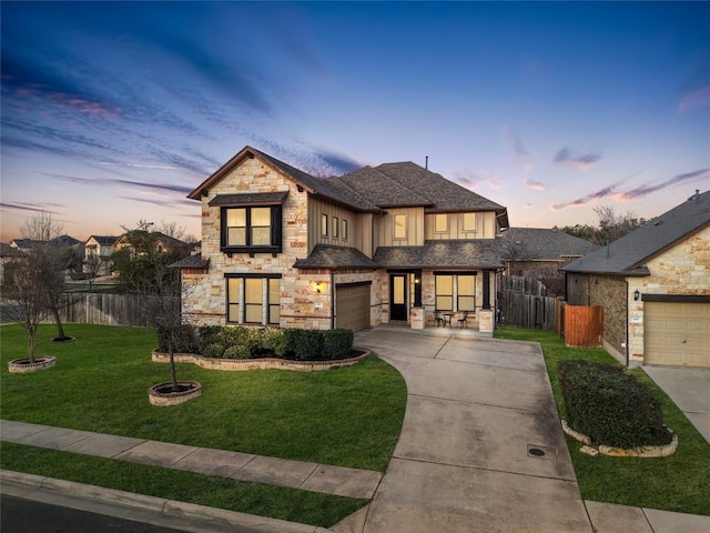 view of front of home featuring driveway, a front lawn, stone siding, and fence