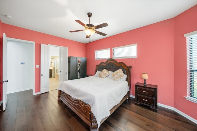 bedroom featuring ceiling fan, baseboards, dark wood-style flooring, and ensuite bathroom